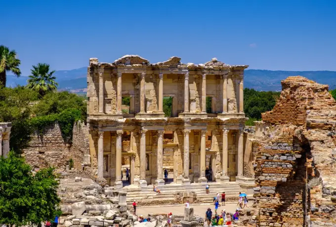 The Library of Celsus at Ephesus with palm trees and hills behind it.