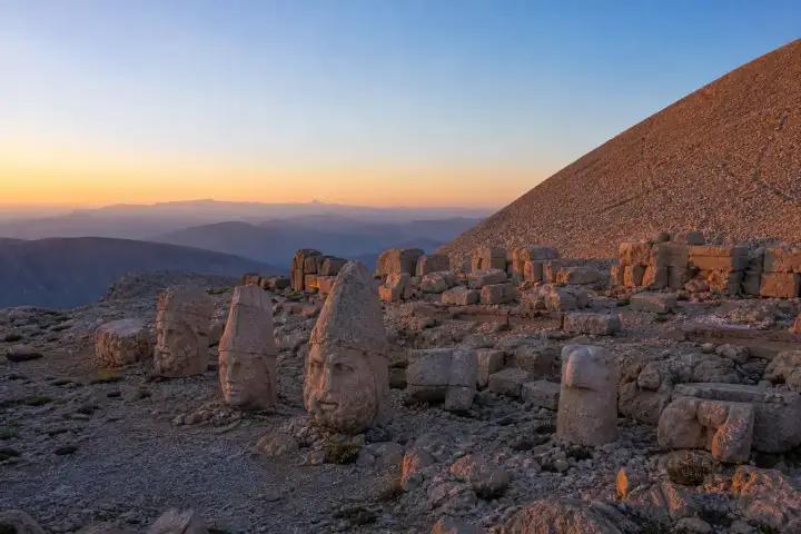 A row of fallen Commagene stone heads on the eastern terrace of Mount Nemrut at sunrise.