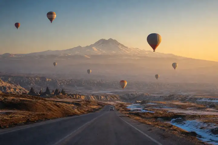 Hot air balloons over the Cappadocia plateau with snow-capped Mount Erciyes near Kayseri.