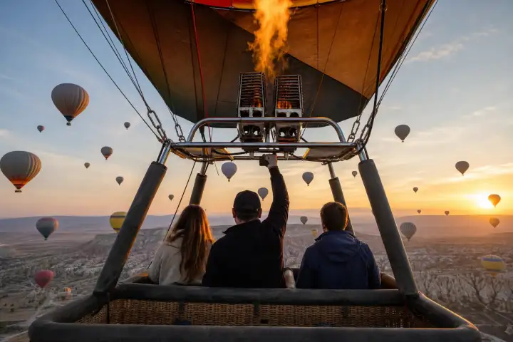A sunrise hot air balloon flight above Cappadocia valleys viewed from inside the wicker basket.