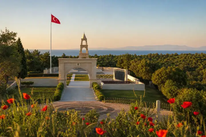 The 57th Regiment Memorial at Gallipoli framed by red poppies with the Dardanelles beyond.