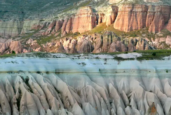 Banded pink and cream cliffs rise above the ridged valley floor of Rose Valley in Cappadocia.