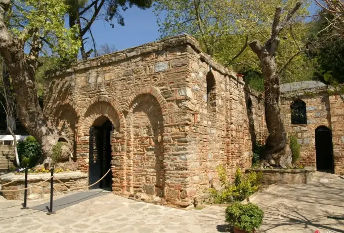 Fresh spring foliage surrounds the arched stone entrance of the House of the Virgin Mary on the hillside above Selcuk.