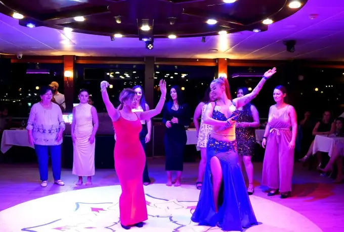 Guests join the performers on the lit dance floor of a Bosphorus dinner cruise in Istanbul.