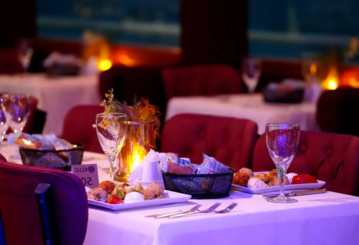 A place setting with mezze dishes and glassware waits on a candlelit table aboard a Bosphorus dinner cruise in Istanbul.
