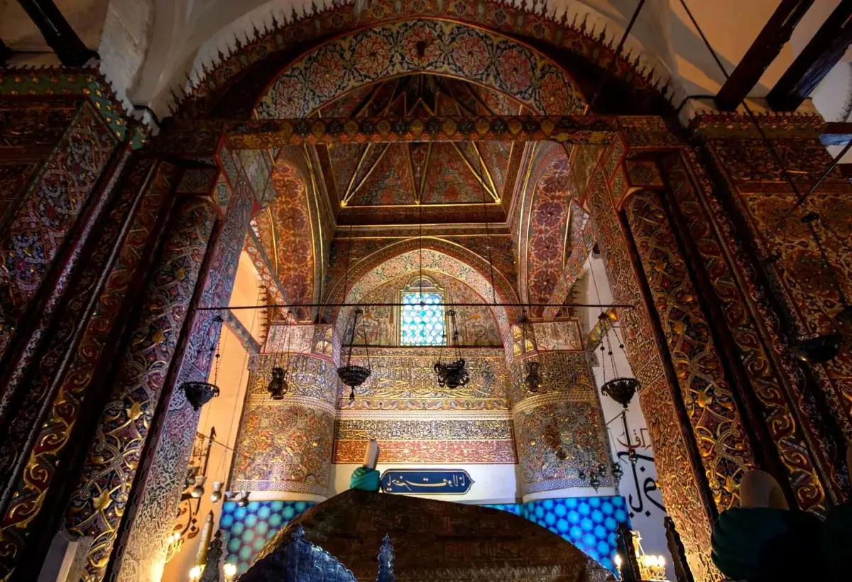 Gilded arabesque arches, hanging lamps and a stained glass window fill the richly painted ceremonial hall of the Mevlana Museum in Konya.