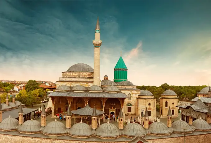 Rows of small lead domes cover the courtyard portico of the Mevlana complex in Konya below the minaret and turquoise tomb dome.