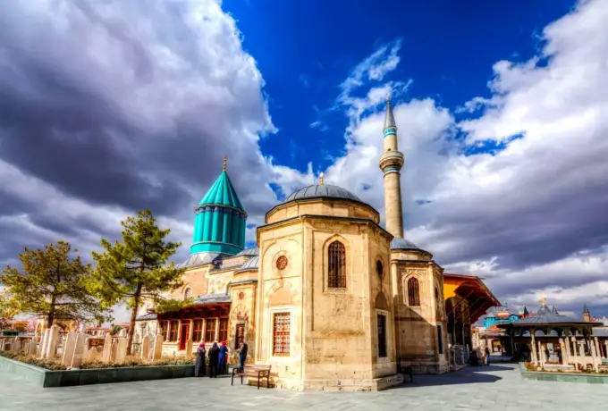 Dark cloud builds over the octagonal mosque and the turquoise conical dome of the Mevlana complex in Konya.