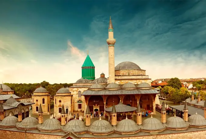 The turquoise dome, mosque and domed courtyard portico of the Mevlana complex in Konya at sunset.