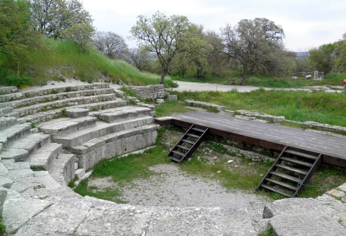Curved limestone tiers surround a timber stage platform in the small odeon at the Troy archaeological site near Canakkale.