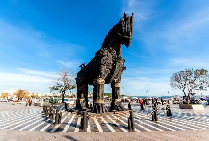 The full-size dark timber Trojan horse stands on the Canakkale seafront promenade under a bright blue sky.