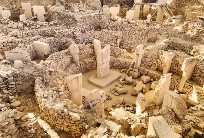 A steep view into the main Gobeklitepe enclosure shows two central pillars on a raised base ringed by a dozen shorter stones.