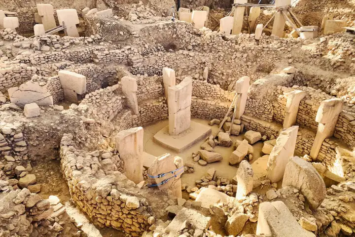 A steep view into the main Gobeklitepe enclosure shows two central pillars on a raised base ringed by a dozen shorter stones.