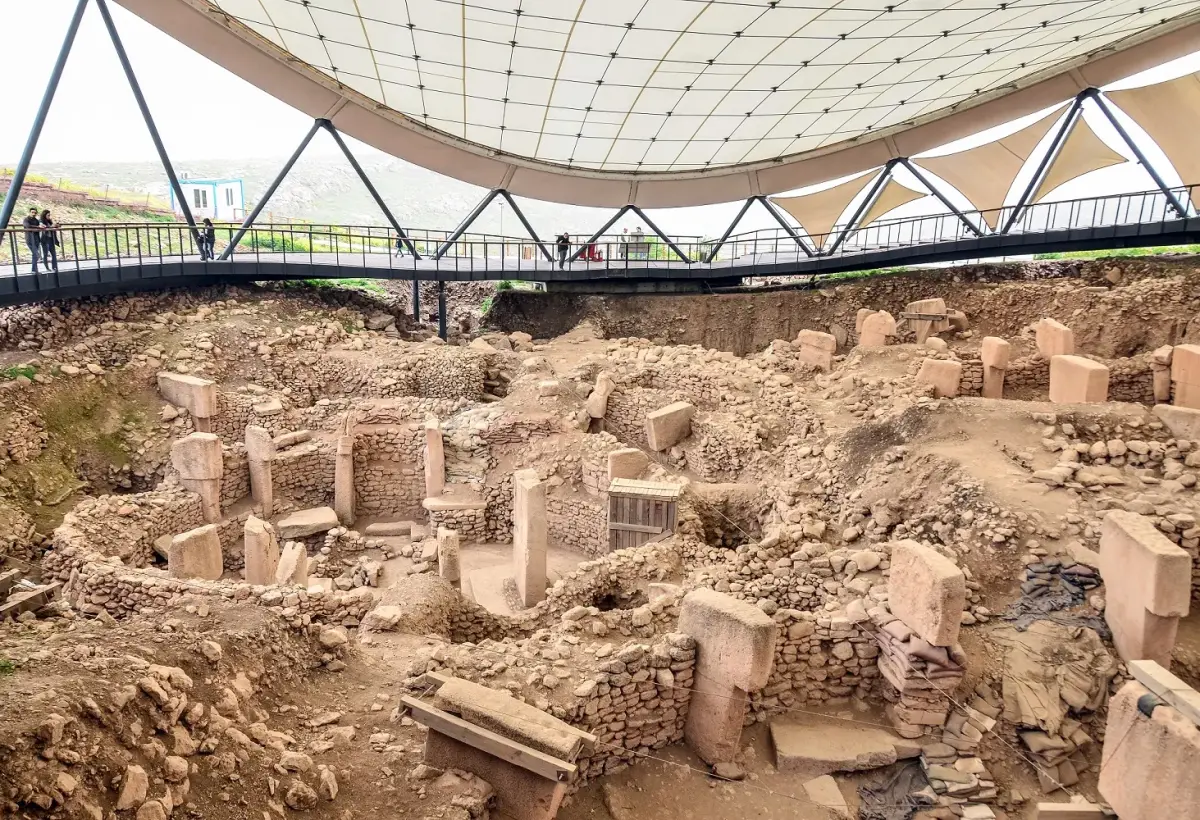 The broad excavation field at Gobeklitepe spreads under its white canopy roof, stone chambers and pillars at different stages of digging.