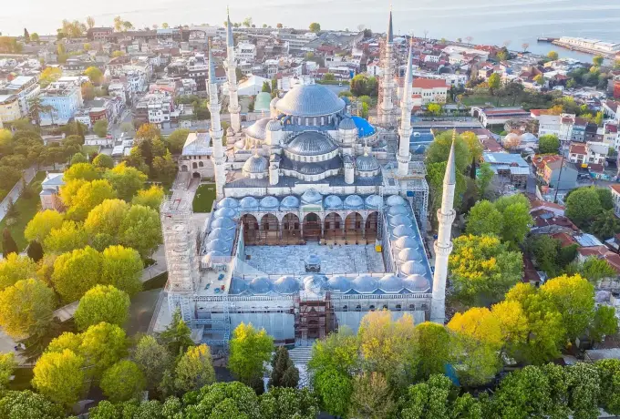 An overhead view of the Blue Mosque complex in Istanbul shows the courtyard, domes and minarets ringed by spring trees.