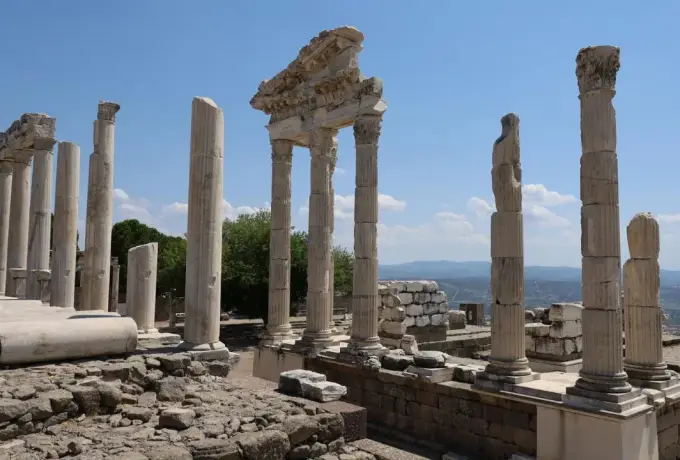 A headless marble statue stands among the columns and fallen blocks of the temple terrace at Pergamon.