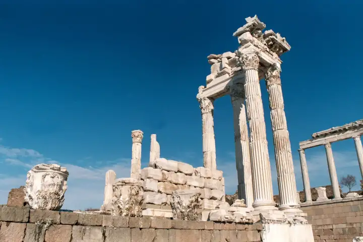 A carved Corinthian capital tops the surviving columns of the Temple of Trajan at Pergamon under a clear sky.