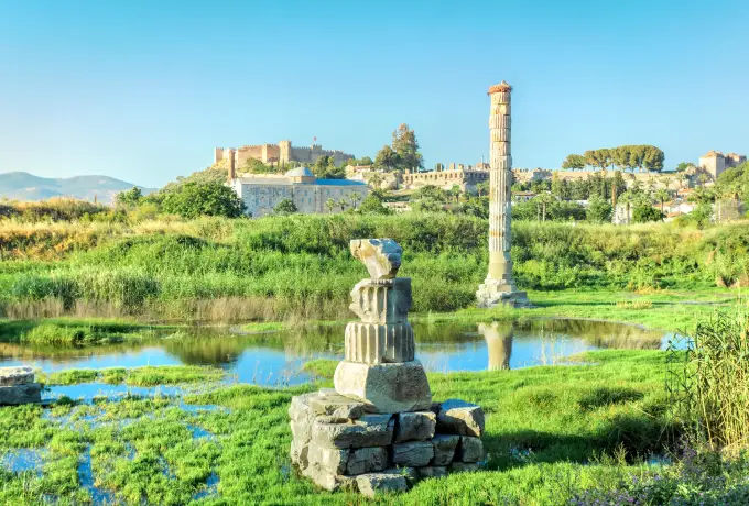 The single re-erected column of the Temple of Artemis stands above green marshland at Selcuk with the castle on the hill behind.