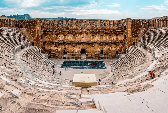 The interior of the Aspendos theatre shows its complete horseshoe of seating facing the tall two-storey stage wall.