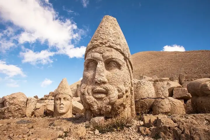 Colossal carved stone heads with pointed crowns lie on the bare terrace of Mount Nemrut in Adiyaman.