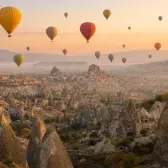 Hot air balloons floating above the fairy chimneys of Goreme in Cappadocia at sunrise
