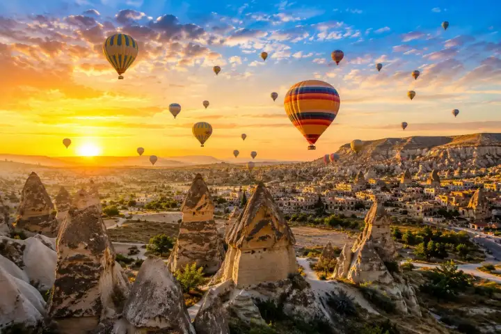 Colorful hot air balloons rise over Goreme's fairy chimneys during a golden Cappadocia sunrise.