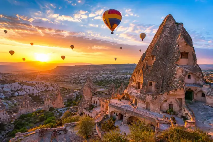Hot air balloons fly above Goreme's carved cave houses and rock formations at sunrise.