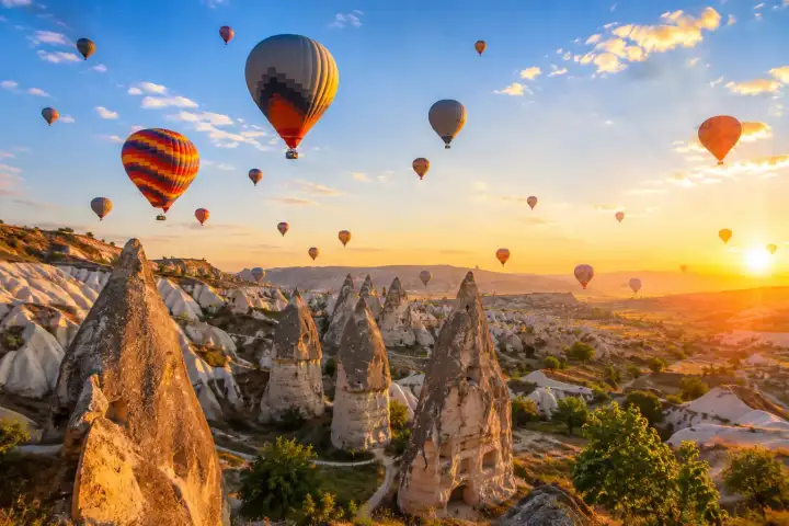 A colorful fleet of hot air balloons drifts over Cappadocia's fairy chimneys at sunrise.