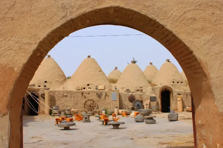 An arched entrance frames Harran's traditional beehive houses and heritage courtyard.